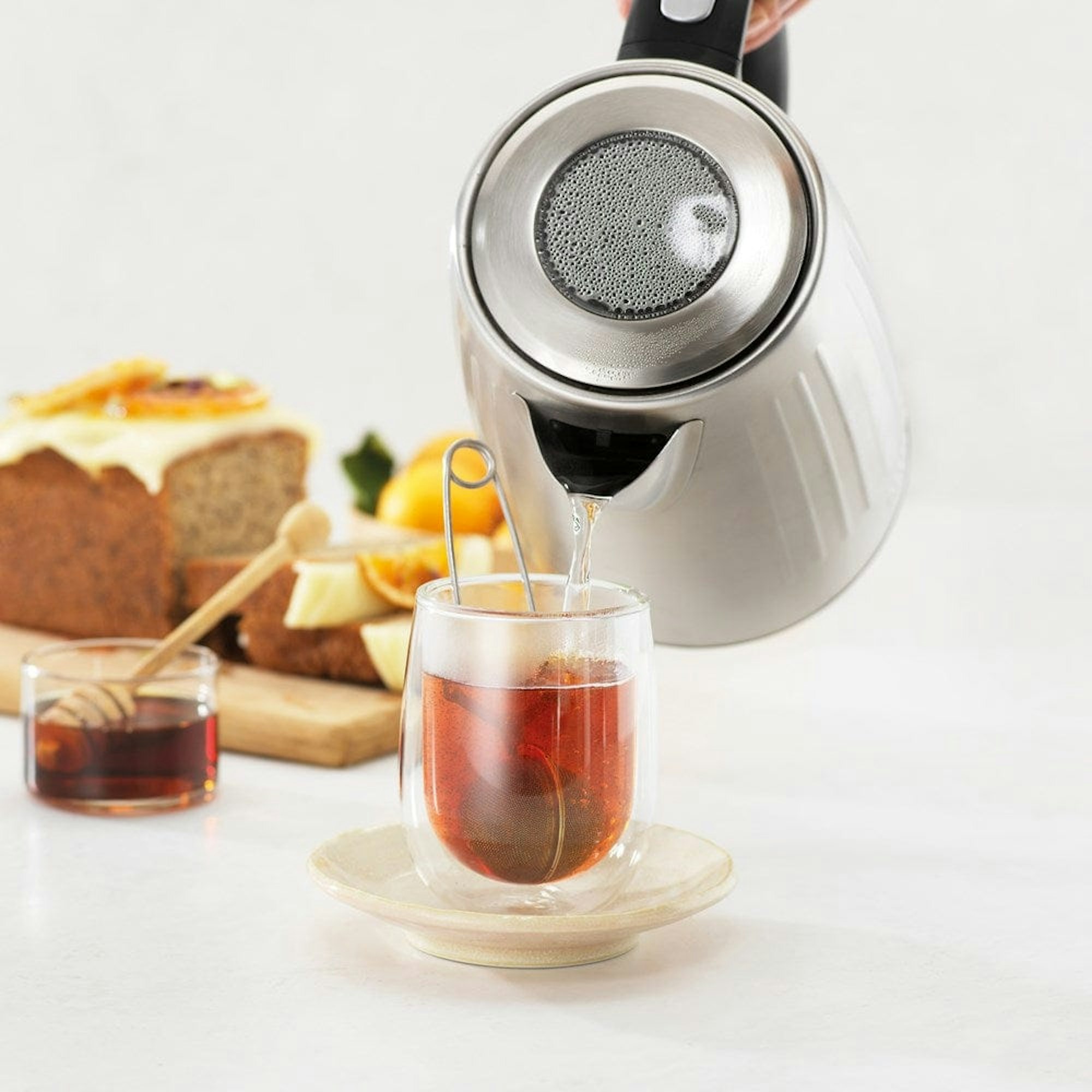 water poured into glass tea cup from kettle